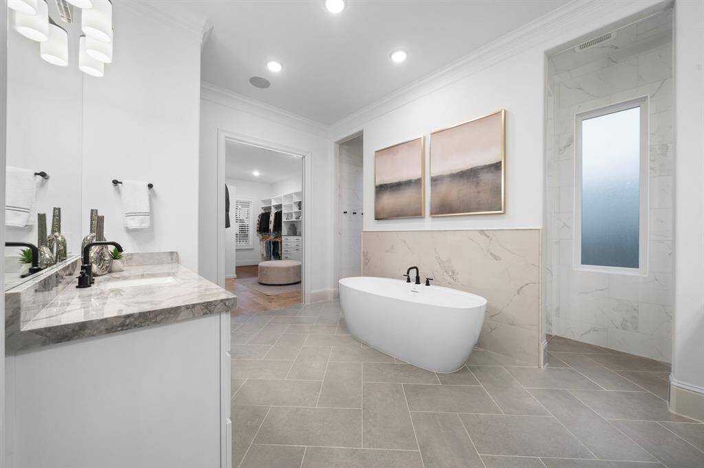 Step into the spa-like bath where custom cabinetry meets dual vanities and direct access to the suite’s expansive walk-in closet with hidden storage.