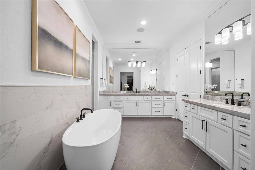 Everyday luxury lives here—double sinks, a deep soaking tub, and expansive counter space are framed by polished surfaces and soft lighting.