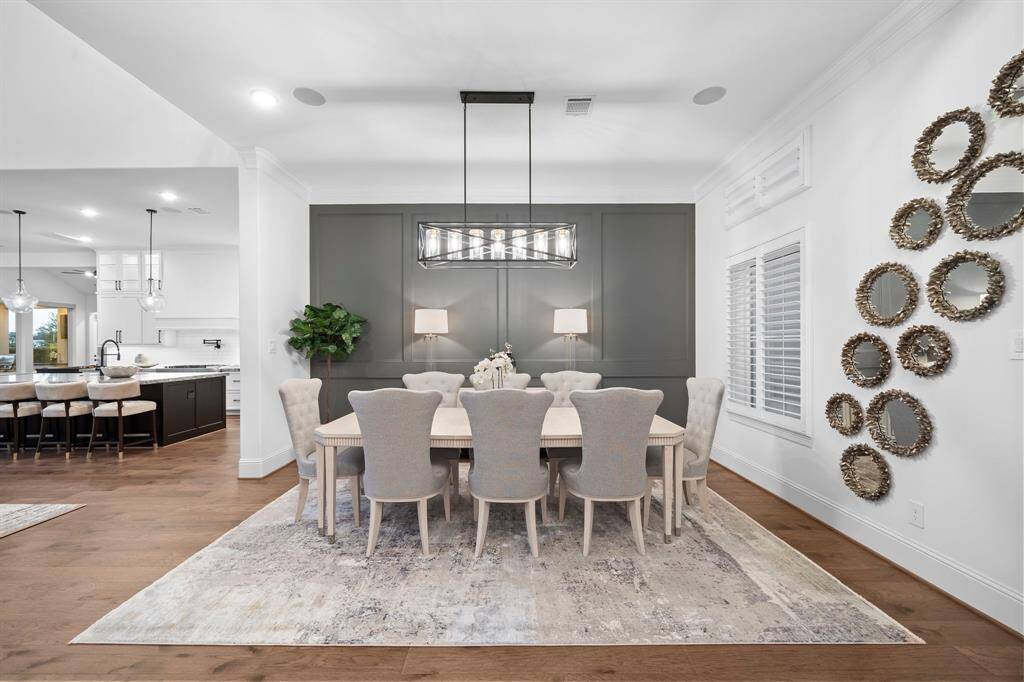 Sophisticated formal dining room features an elegant custom accent wall, designer chandelier, and a spacious layout for effortless gatherings. Wide-plank hardwood floors, luxe finishes, and easy access to the gourmet kitchen set the stage for unforgettable dinner parties and celebrations.