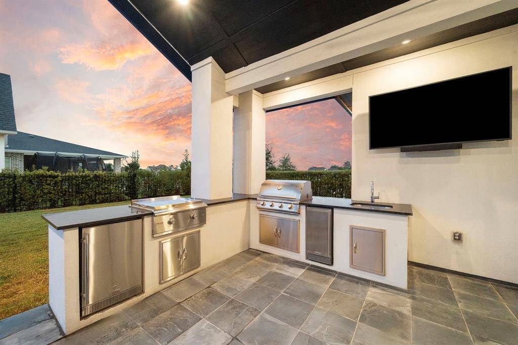 The built-in kitchen includes stainless appliances, a sink, and prep surfaces—designed for convenience during outdoor cooking and weekend gatherings.