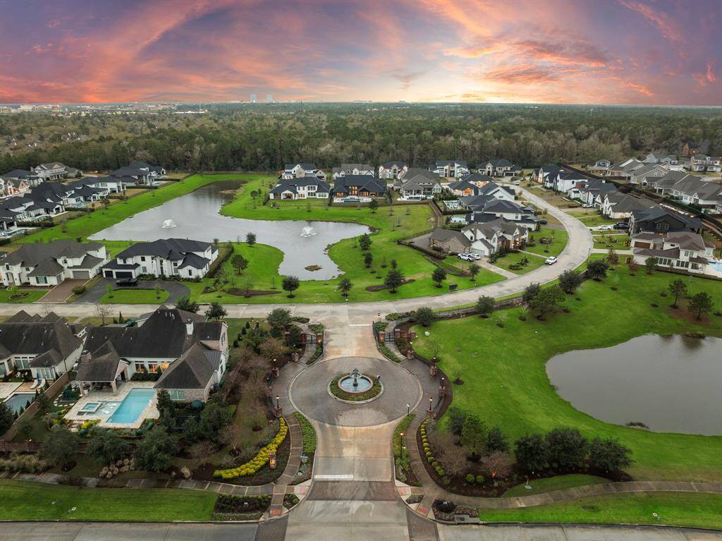 Aerial perspective showcases the luxurious Stillwater neighborhood, featuring meticulously landscaped grounds, sparkling lakes with fountains, and impressive estates on expansive lots. Residents enjoy privacy, refined gated entry, and a serene setting near top shopping, restaurants, and award-winning schools.