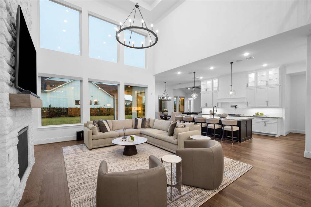 The living area's full-height windows draw in natural light across the hardwoods, while clean sightlines connect the living area to the kitchen and covered patio beyond.