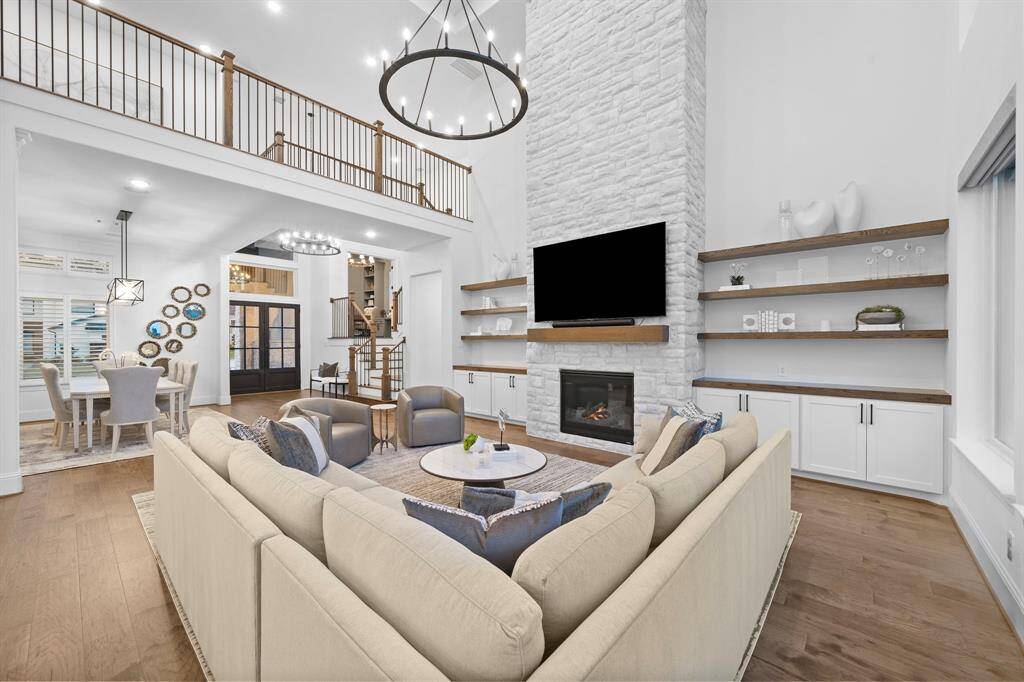 A white brick fireplace climbs to the ceiling between built-in cabinetry and floating shelves, grounding the room with texture and warmth.
