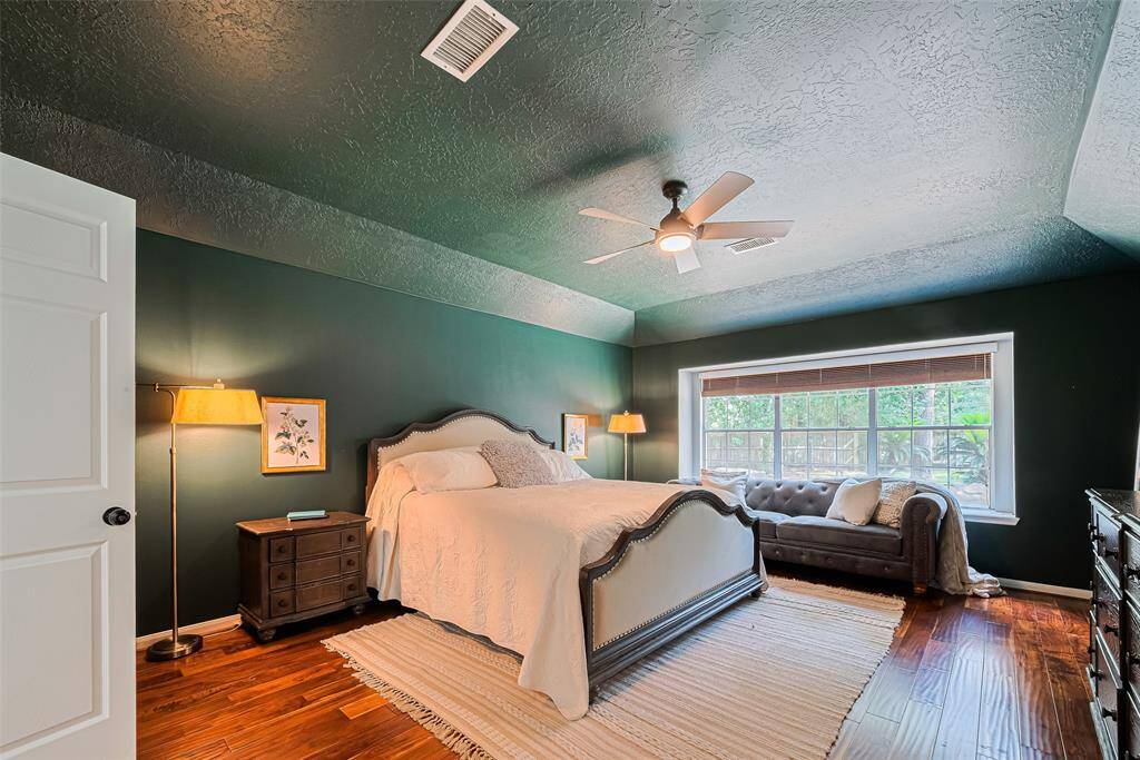 Spacious Primary bedroom with rich green walls, features a large window for natural light creating a warm and inviting space.