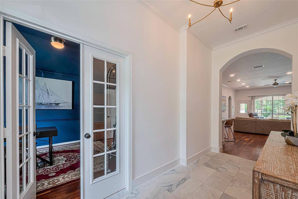 A bright entry with marble flooring opens to a spacious living area, while a cozy office/flex room with French doors is the first room on the left.