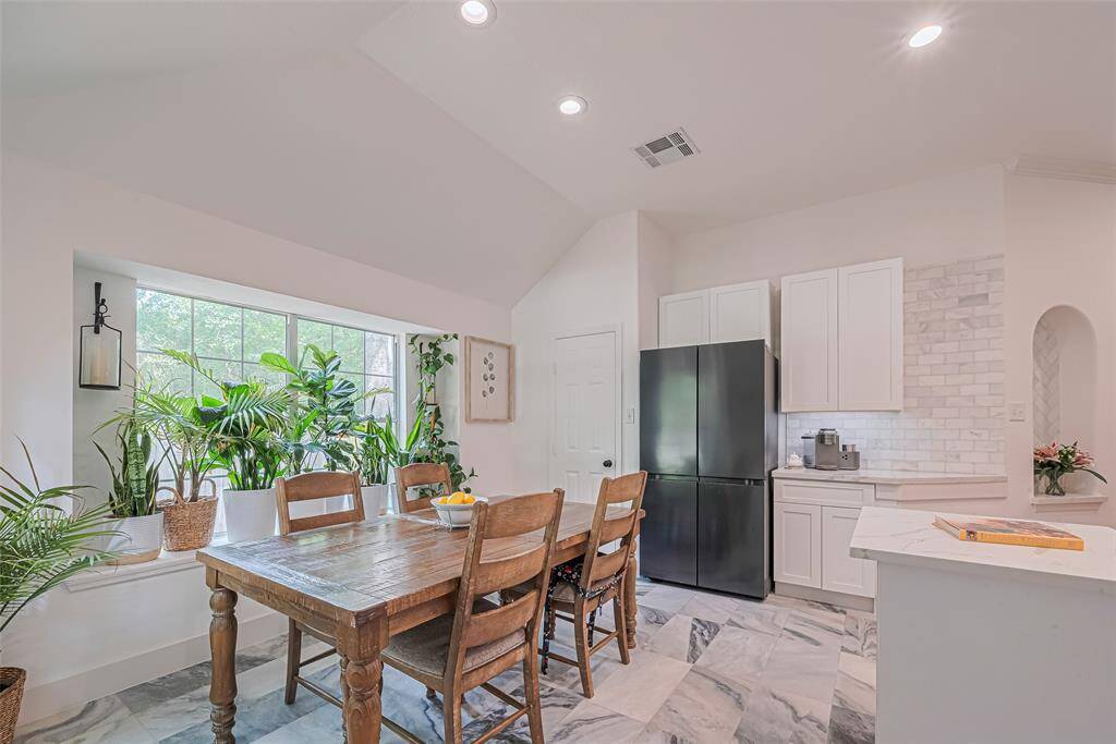 This kitchen includes a dining area with a large picture window accented by the vaulted ceilings