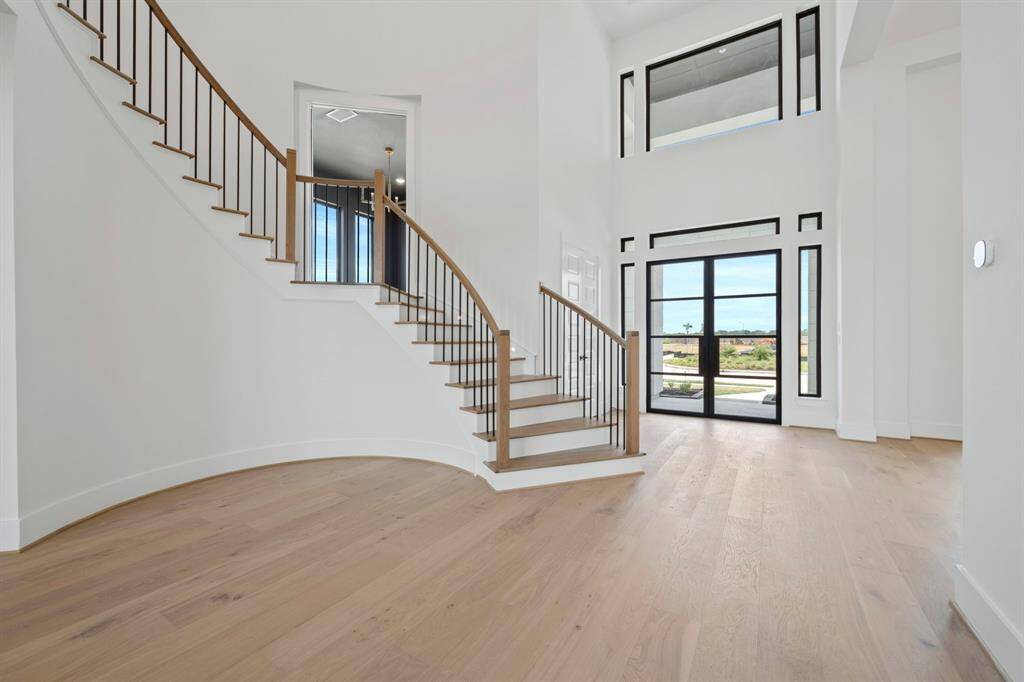 Grand Foyer view entering through the gorgeous double iron front doors with sites into the elegant Formal Dining Room, elevated two-story Living area, winding staircase and curved catwalk with lots of design appeal is coming along beautifully. Gorgeous hardwood flooring is soon to come that will run throughout.