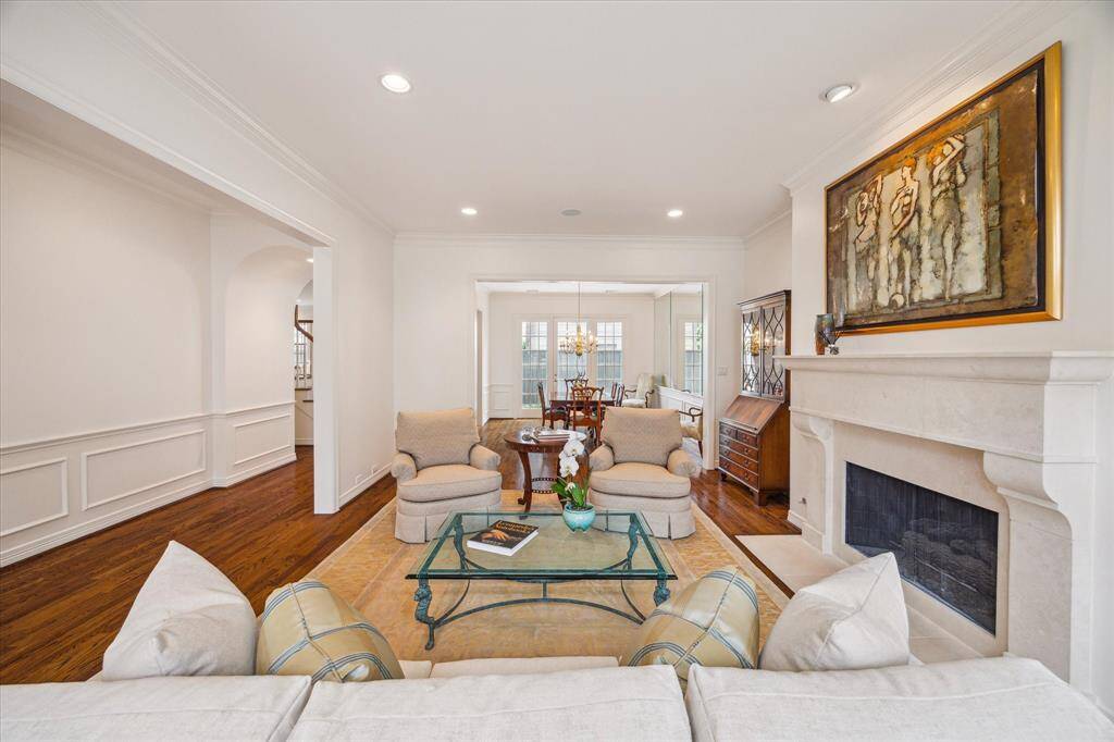 Living Room - Flowing seamlessly into the dining room, other notable features in the living room and foyer include crown molding, wainscoting (foyer), high ceilings and art lighting over the fireplace. Whole home was freshly painted (2025).