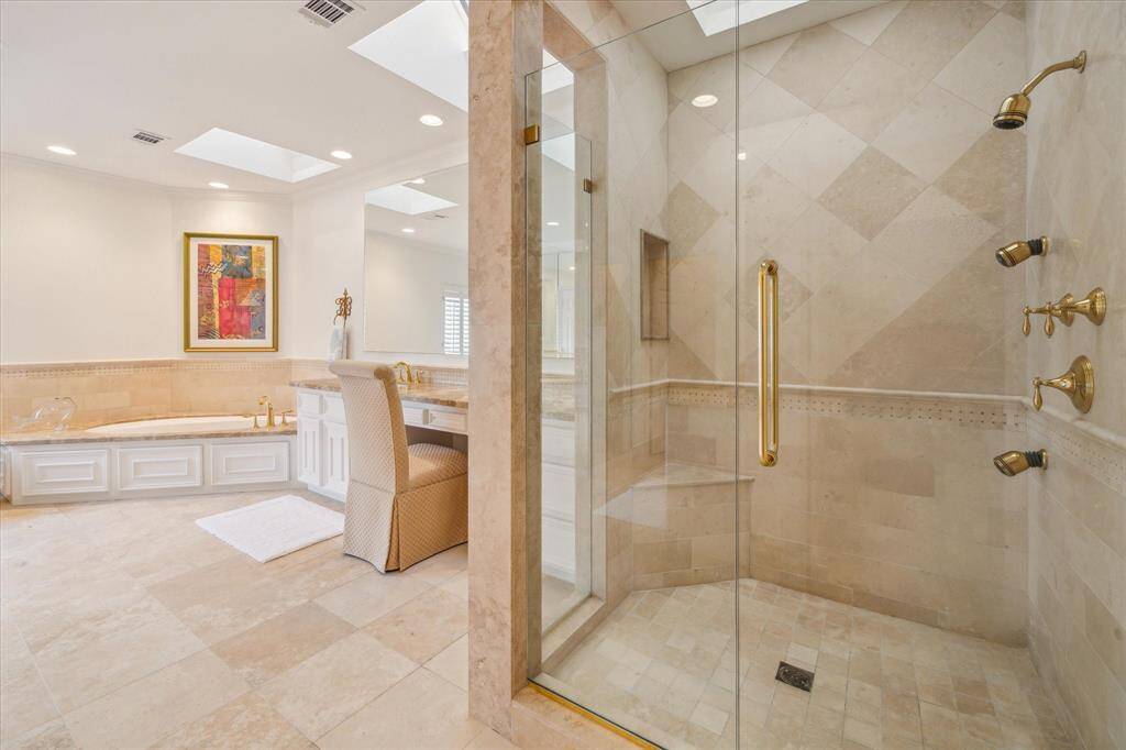 Primary Bath - Light filled, spa-like marble clad primary bath has oversized, bespoke walk-in shower, soaking tub, dual dressing areas with vanity and sky lights.