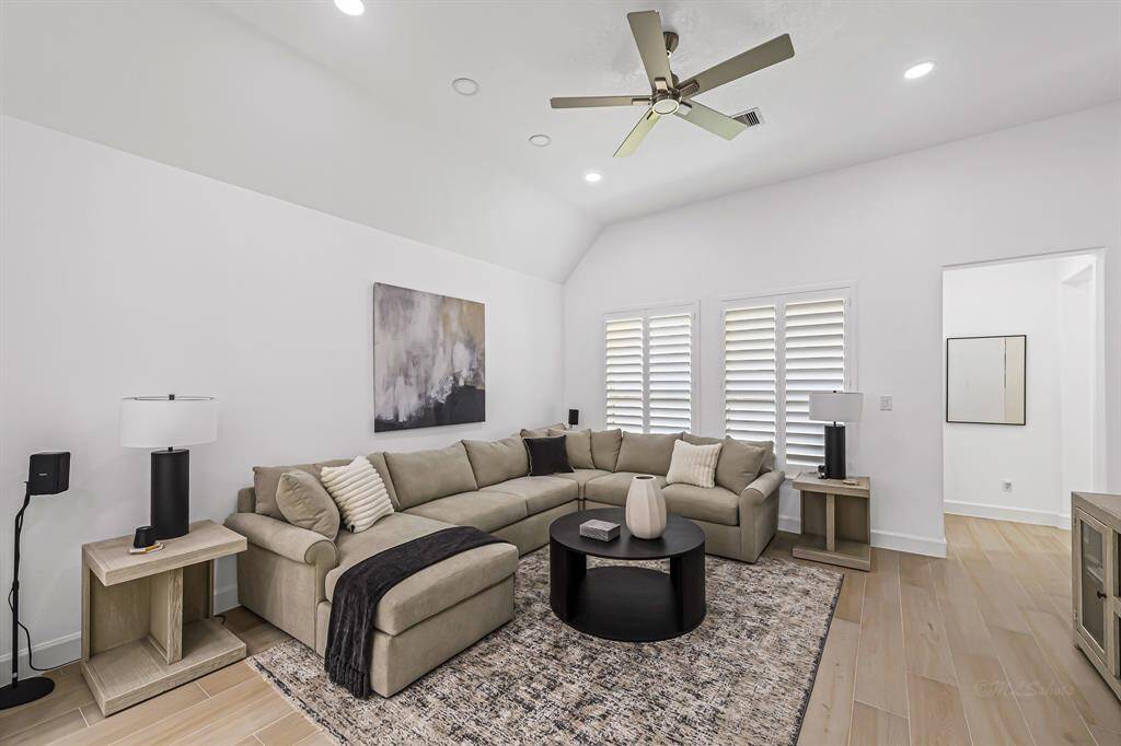 The family room is a perfect balance of comfort and style, featuring large windows adorned with classic plantation shutters that fill the space with soft, natural light.