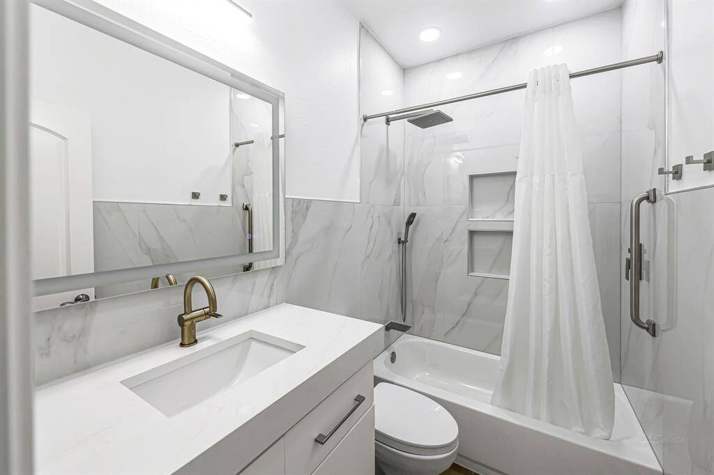 This fully upgraded secondary bathroom feels fresh and luxurious from top to bottom. Featuring a relaxing tub, quartz countertop, porcelain tiles and sleek rainfall shower head, every detail has been thoughtfully chosen for comfort and style. The contemporary vanity, modern fixtures, and illuminated mirror add a polished touch, creating a spa-like experience perfect for guests or daily use.