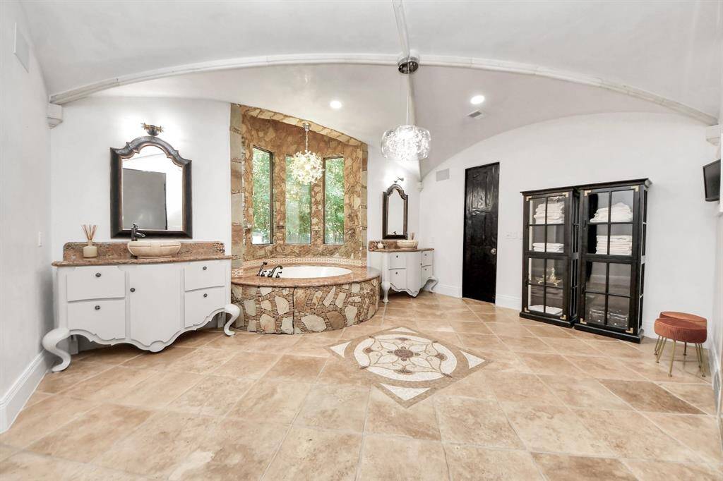 Indulge in luxury with double sinks, a custom jet tub, a shower, and two spacious closets featuring elegant custom wood built-ins.