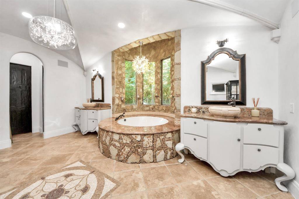 Indulge in luxury with double sinks, a custom jet tub, a shower, and two spacious closets featuring elegant custom wood built-ins.