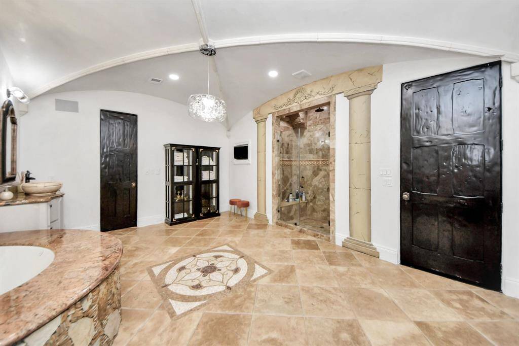 Indulge in luxury with double sinks, a custom jet tub, a shower, and two spacious closets featuring elegant custom wood built-ins.