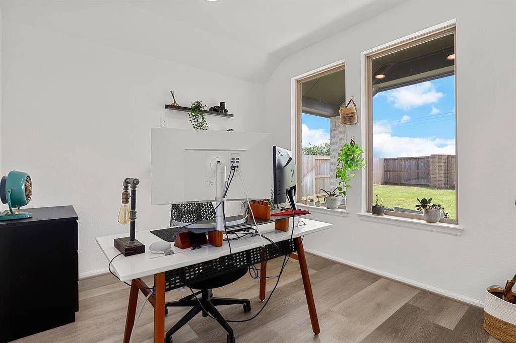 Bright home office with large windows, providing ample natural light and a view of the backyard.