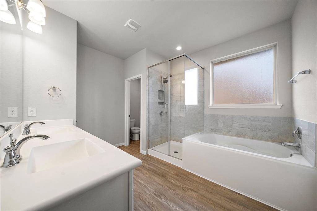 The primary bathroom is designed for relaxation, featuring double sinks, a separate shower and a luxurious soaking tub. Whether you prefer a quick rinse or a long soak, this bathroom offers the perfect balance of comfort and functionality. The spacious layout and clean design make it an ideal space to unwind after a long day.