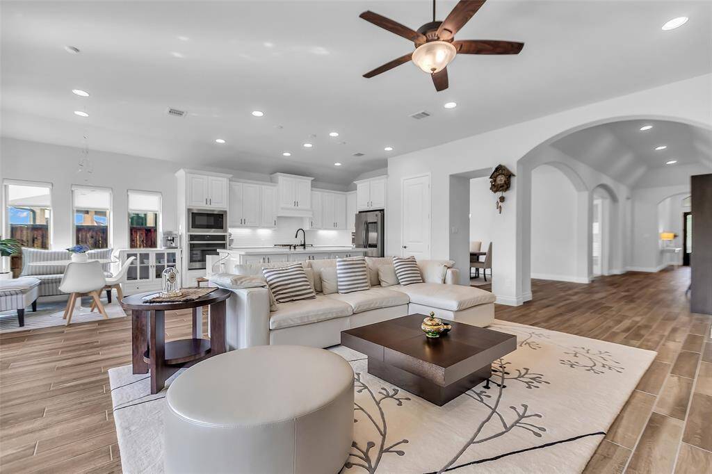 The family room is a serene and inviting space, offering breathtaking views of the tranquil waterfront and lush greenbelt just beyond. A beautiful floor-to-ceiling stone fireplace creates a cozy ambiance.