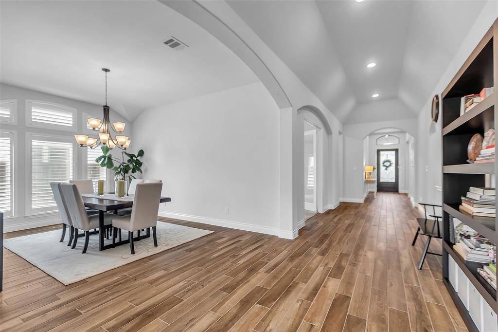 The entryway of this home is a true testament to refined design and timeless elegance and sets the tone for the home, inviting you to explore its seamless balance of luxury and comfort.  As you step inside, your eyes are immediately drawn to the soaring vaulted ceilings, and graceful arches.   The continuity of the wood-look ceramic tile flooring extends a warm welcome, effortlessly blending beauty with practicality.