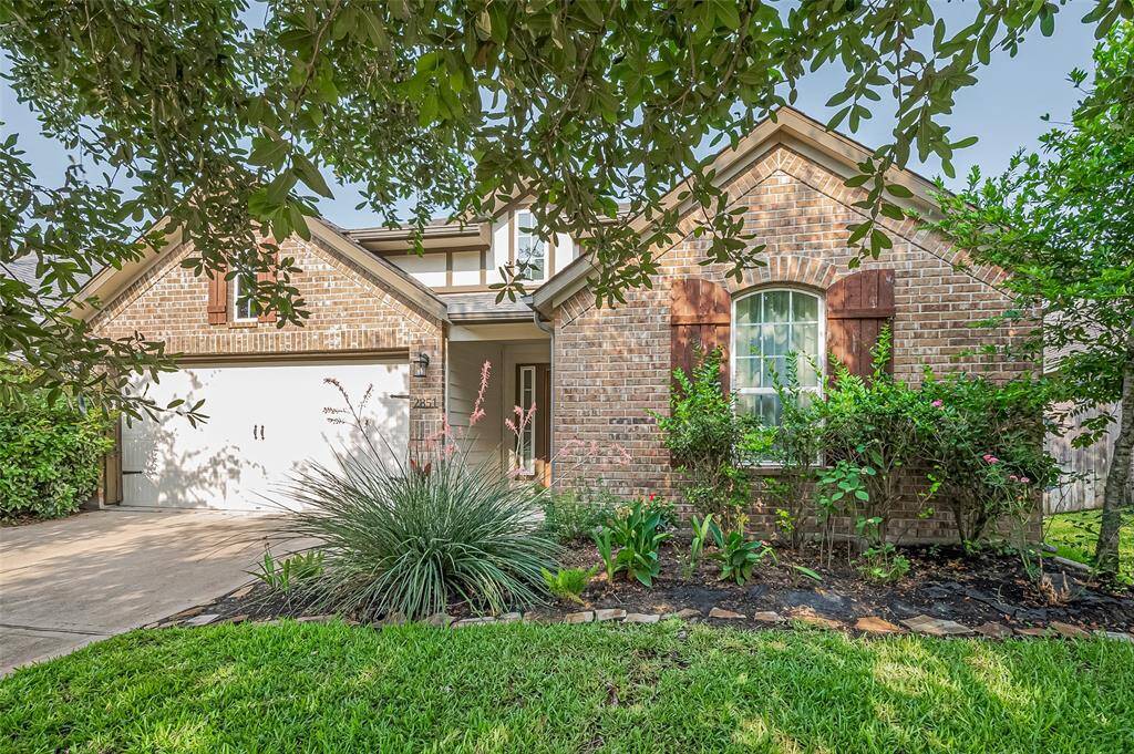 A warm welcome begins at the curb, where plant beds and a vibrant green lawn frame the rich, rustic brick façade. The interplay of light and shadow across the textured exterior hints at the care woven into every corner of the property.