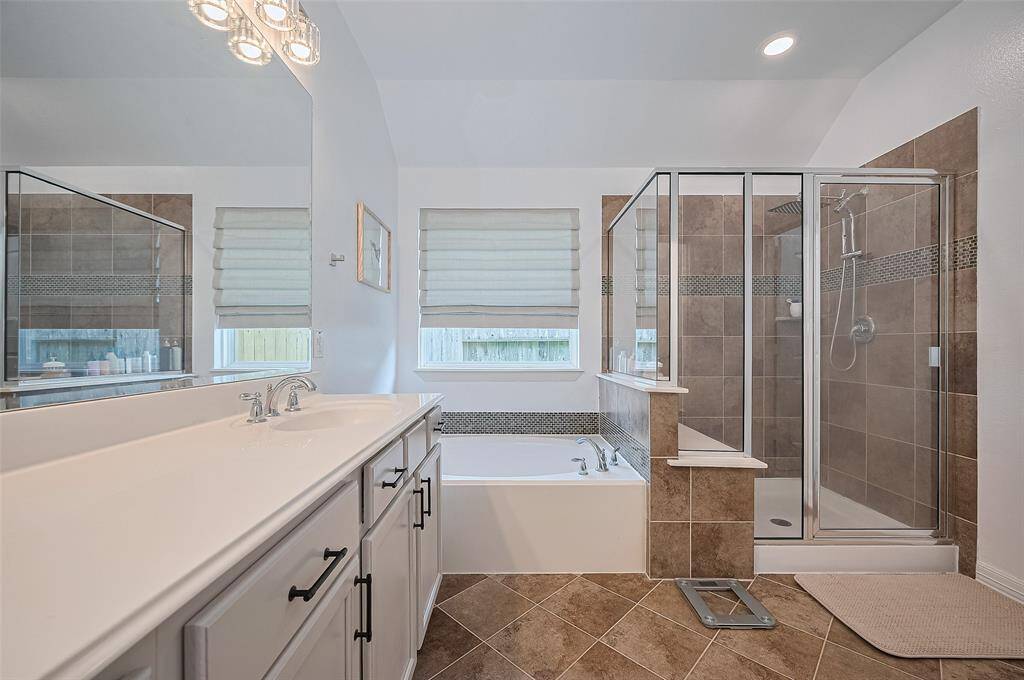 A dual-sink vanity provides space to prepare and unwind, while the deep soaking tub and separate glass-enclosed shower invite quiet moments of recharge.