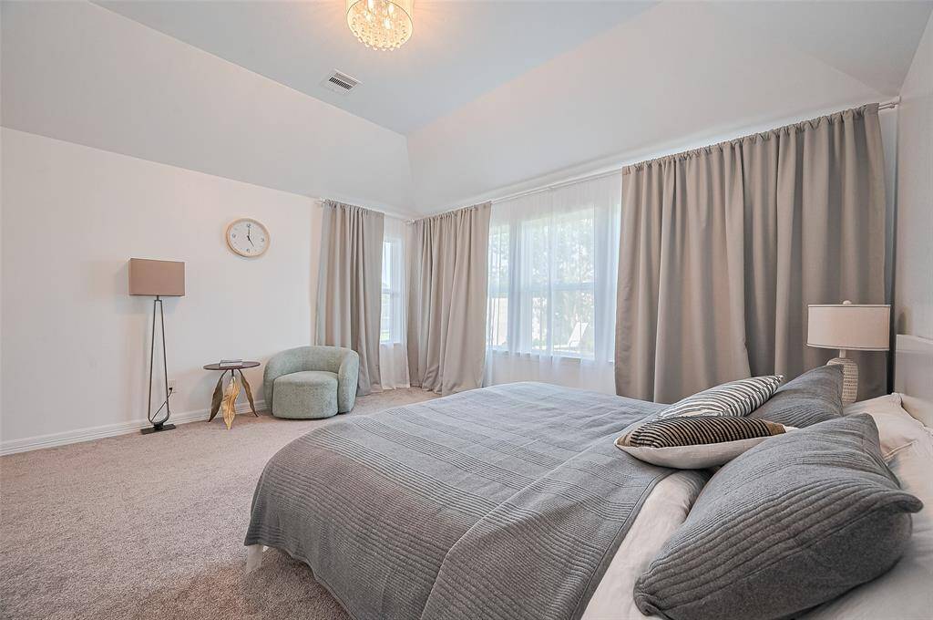 Soft carpeting, high ceilings, and large windows fill this bedroom with comfort and light.