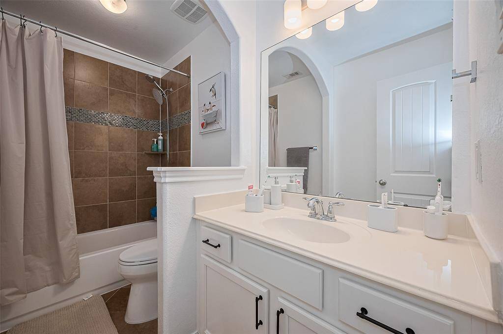 Thoughtfully arranged, this bathroom balances practicality with style—featuring a refined vanity and a classic tub-shower setup beneath soft lighting.