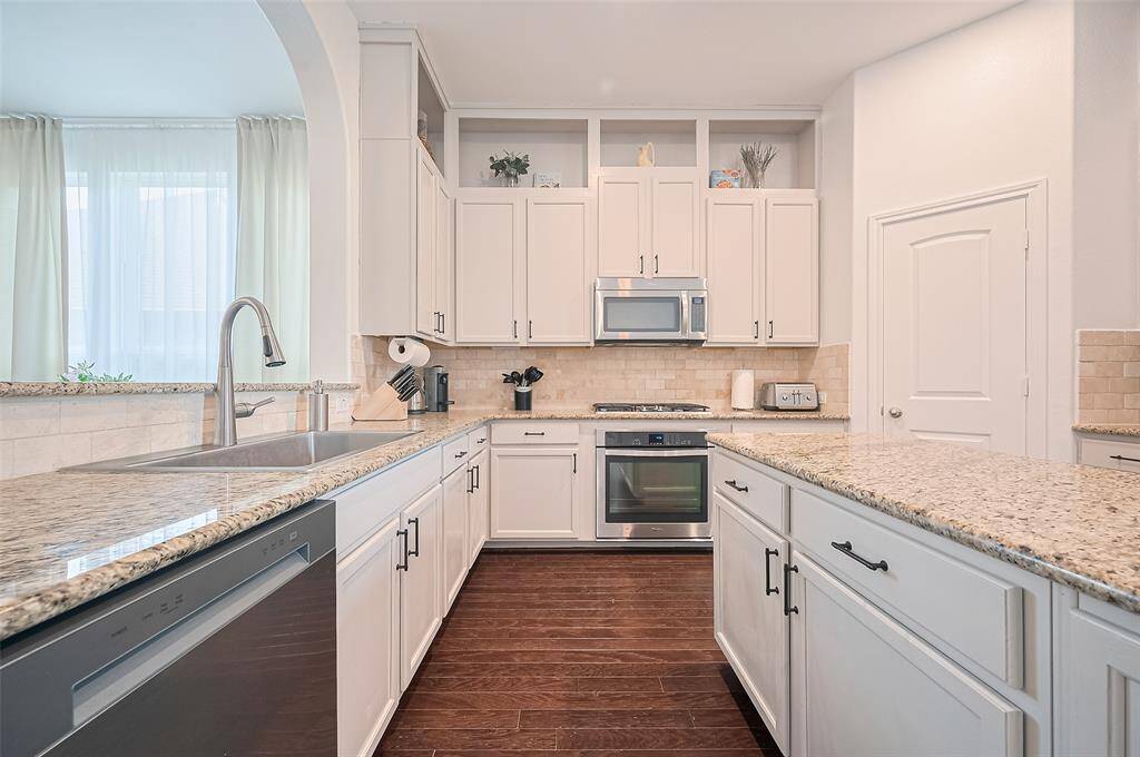 The kitchen impresses with expansive countertops, a tasteful backsplash, and an abundance of cabinetry that keeps everything within reach. The kitchen island provides additional prep space and connects seamlessly to the rest of the home.