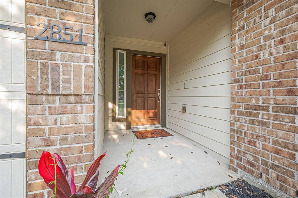 The recessed entryway features a handsome front door with a sidelight, surrounded by a balance of classic brick and smooth cement board siding.