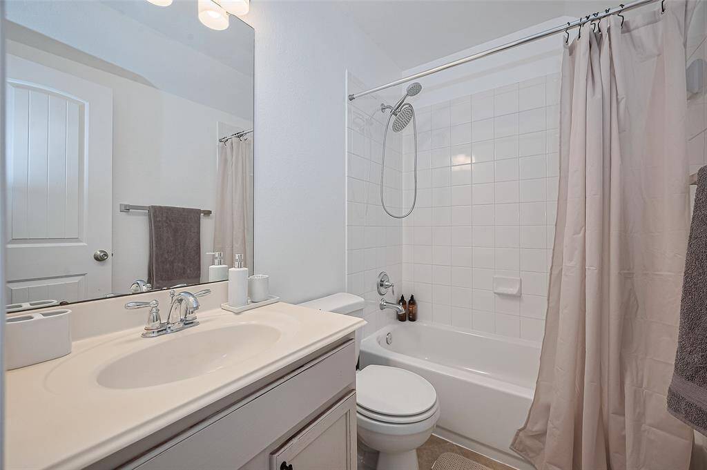 This bathroom features a classic tub-shower combination and a well-lit vanity that reflects both function and finesse.