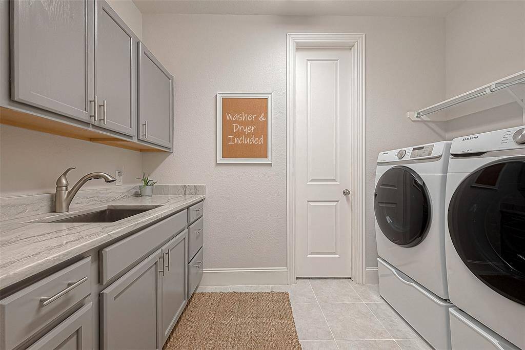 Large laundry room with abundant storage and deep stainless steel sink.  Front load washer & dryer stays with the house.
