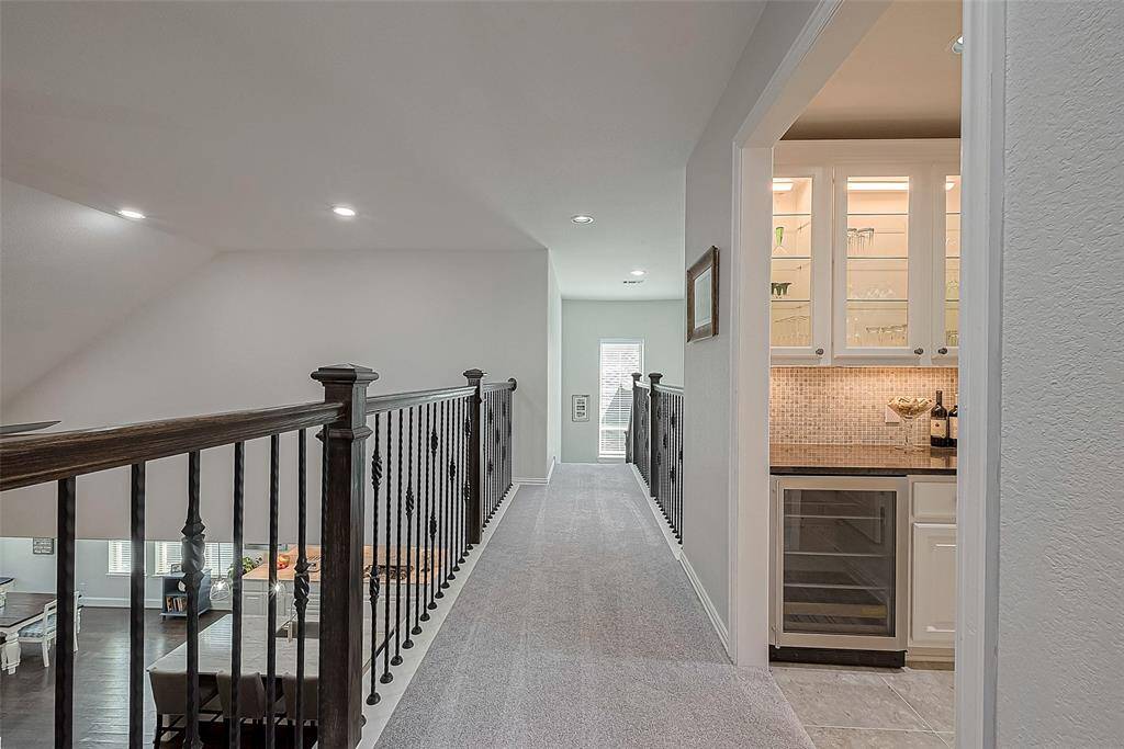 Walkway overlooking living room and kitchen with beautiful wrought iron spindles.