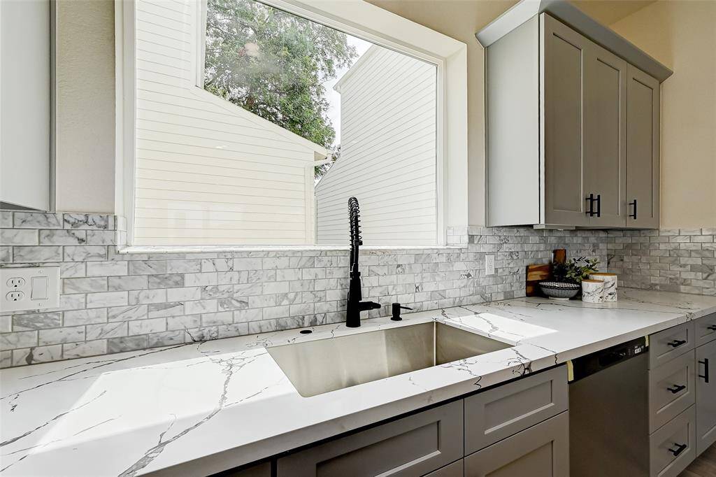Under mount farm sink style with marble stone backsplash.