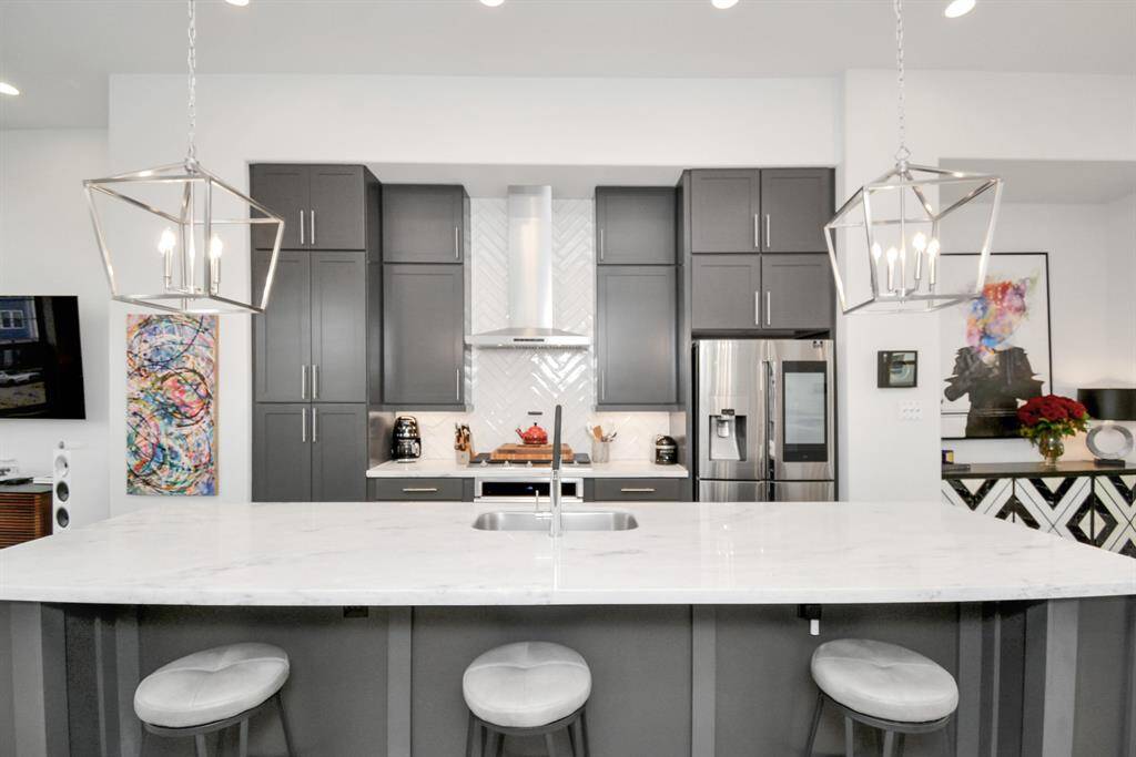 Experience luxury living with 12-ft ceilings and an open-concept design. Entertain effortlessly around the stunning 12-ft marble island, featuring a beverage refrigerator. The kitchen boasts a gas cooktop and soft-close cabinetry, perfect for any home chef.