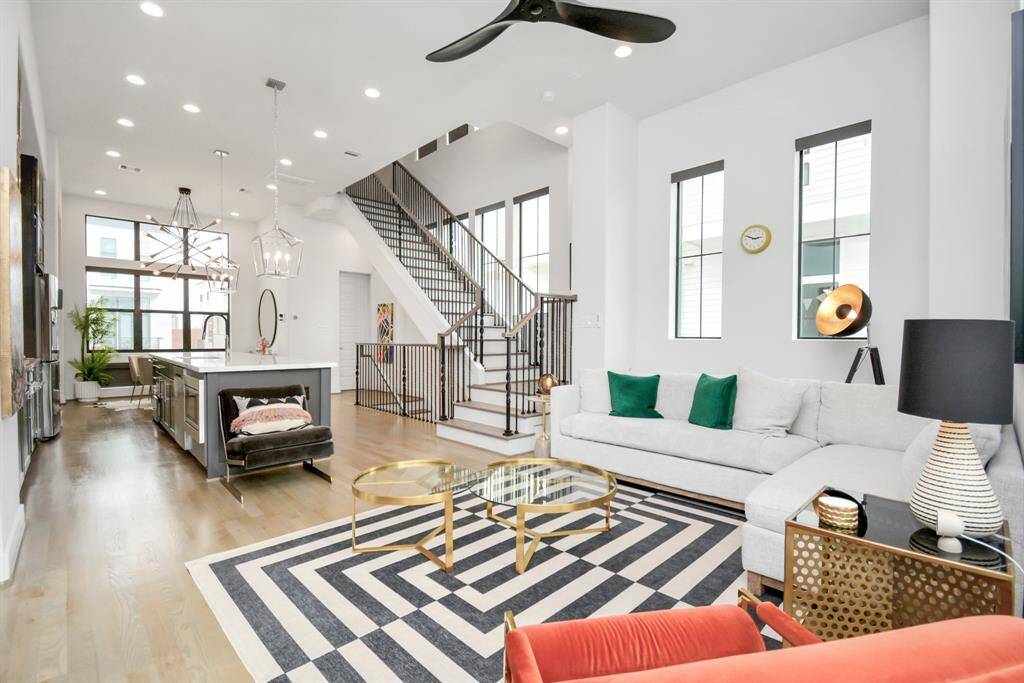 Modern open-plan living space with high ceilings and abundant natural light. Features a sleek kitchen with an island, and stylish light fixtures.