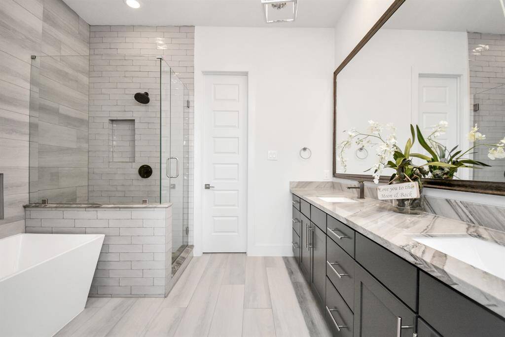Luxurious primary bathroom featuring a separate shower, a relaxing tub, and elegant double sinks.