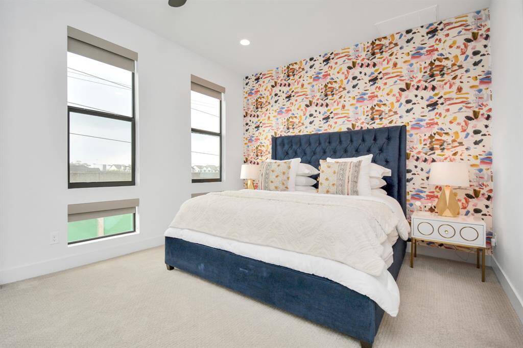 Spacious primary bedroom featuring plush carpet and a vibrant accent wall. Wallpaper removal available upon request.