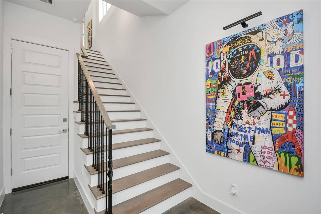 Elegant entryway with sleek stained concrete floors, providing access to the first-floor bedroom and spacious 2-car garage.