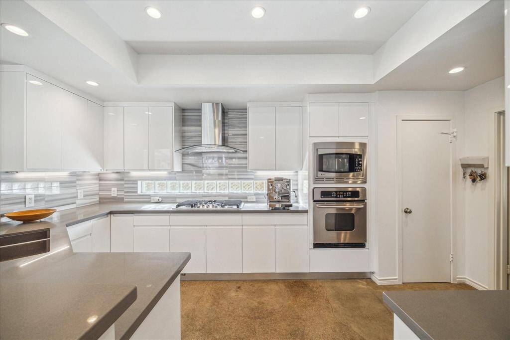 RENOVATED KITCHEN IS STUNNING WITH GLEAMING COUNTERS, UPGRADED CABINETS, CUSTOM BACKSPLASH, AND SS APPLIANCES.