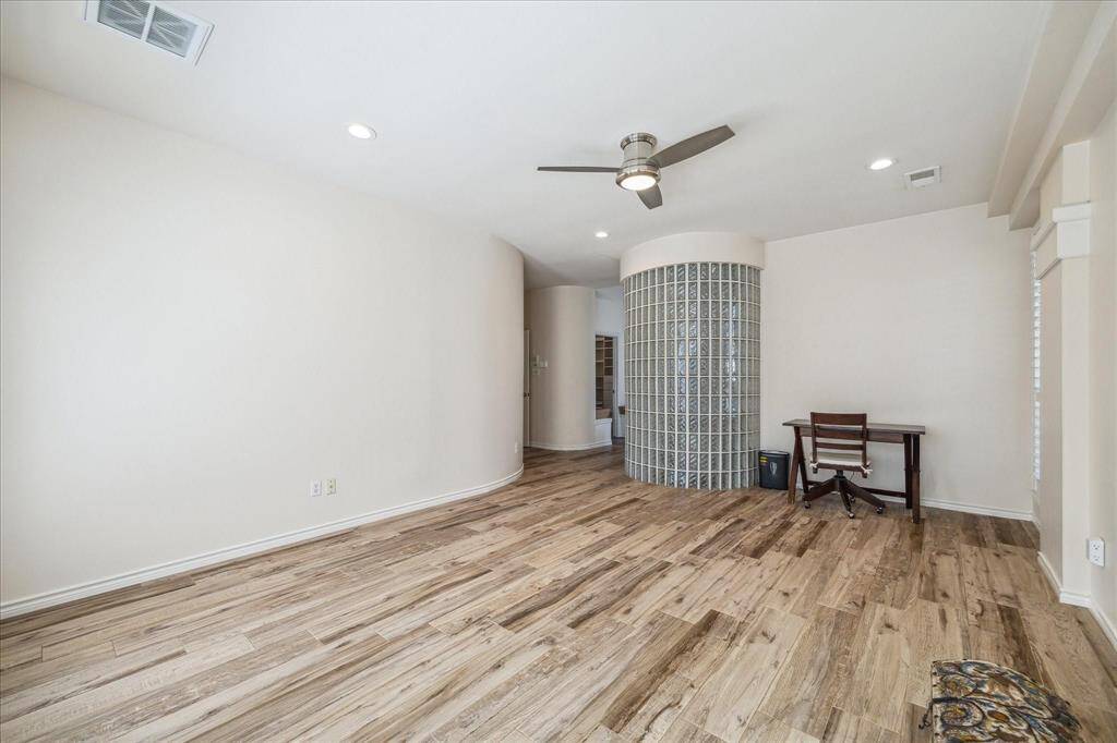 OPPOSITE VIEW OF THE PRIMARY BEDROOM. THE WOOD-LOOK TILE FLOORING CONTINUES INTO THE BEDROOM.