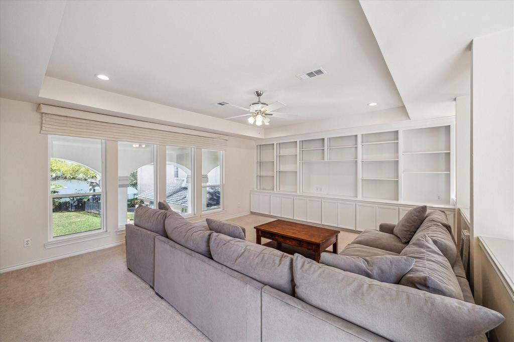 UPSTAIRS YOU'LL FIND A GENEROUSLY SIZED GAME ROOM; COMPLETE WITH A WALL OF BUILT-IN STORAGE, TRAY CEILING, AND CUSTOM WINDOW COVERINGS.