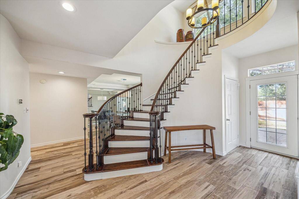 HARDWOOD STEPS WITH WHITE RISERS LOOK ELEGANT WITH THE WROUGHT IRON BALUSTERS.