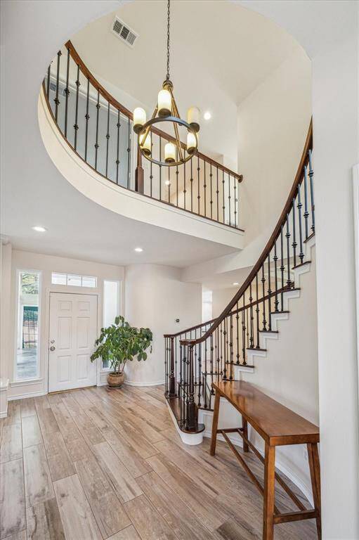 GRAND ENTRANCE OFFERS A SOARING 2-STORY CEILING, SWEEPING STAIRCASE, AND WOOD-LOOK TILE.
