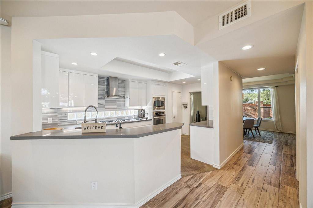A LONG BREAKFAST BAR OVERLOOKS THE KITCHEN CREATING A HOMEWORK/CASUAL DINING AREA.