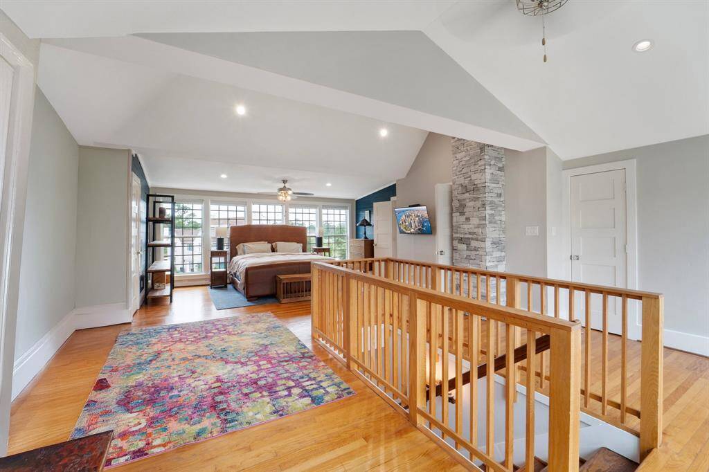 Located on the third floor, this expansive  primary bedroom boasts a wall of windows that flood the space with natural light, soaring high ceilings, a coffee bar and beautiful hardwood flooring for a bright and airy retreat.