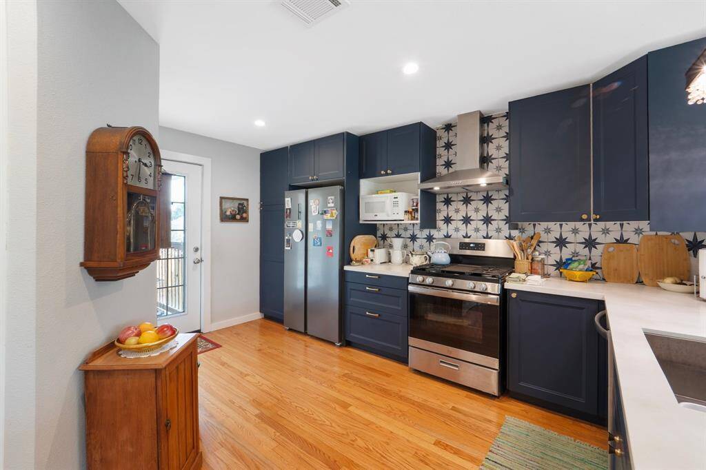 The kitchen shines with stainless steel appliances, custom-painted cabinets, and a sleek modern backsplash—blending style and function for the perfect culinary space.