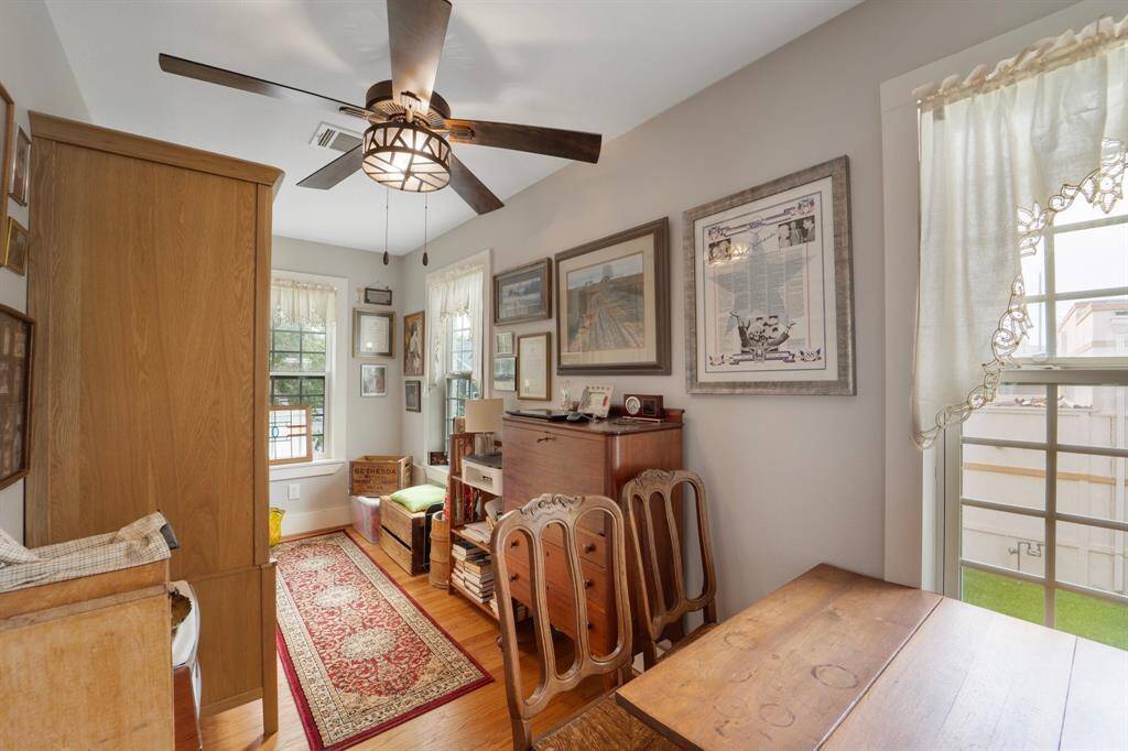The apartment also features a bright and inviting home office, complete with multiple windows that fill the space with natural light, a ceiling fan for comfort, and elegant hardwood floors that add a touch of sophistication.