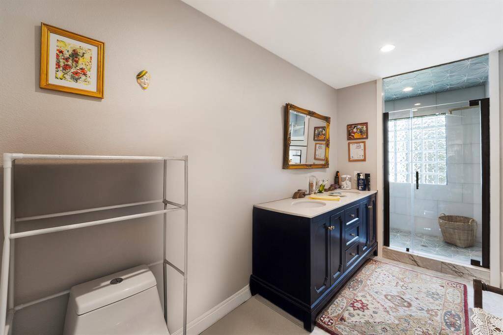This stylish bathroom features a double sink vanity, a large tiled walk-in shower with a sleek glass enclosure, and recessed lighting that creates a bright and inviting atmosphere.