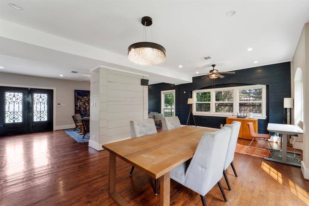 The elegant dining room showcases beautiful hardwood flooring, a large framed window that fills the space with natural light, and a modern chandelier that adds a touch of sophistication.