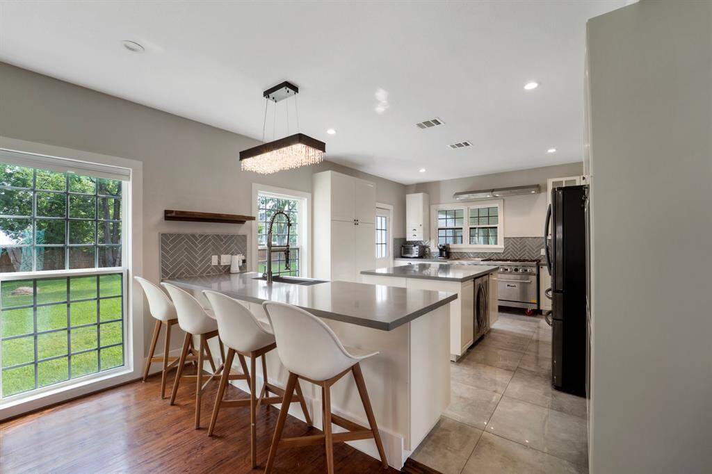 Located just off the dining room, the kitchen is a chef’s dream with a spacious peninsula, center island, recessed lighting, and durable tile flooring—perfect for cooking and entertaining alike.