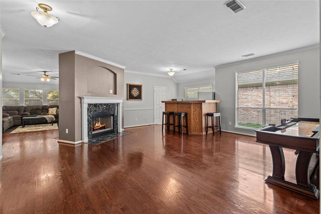 Spacious multipurpose room features a cozy fireplace and flexible layout—currently used as a game room, but generously sized to accommodate both a formal living and dining area.